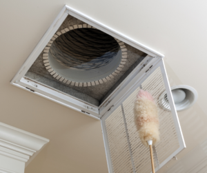A home's dirty air duct in the ceiling, with vent opened in front of it.